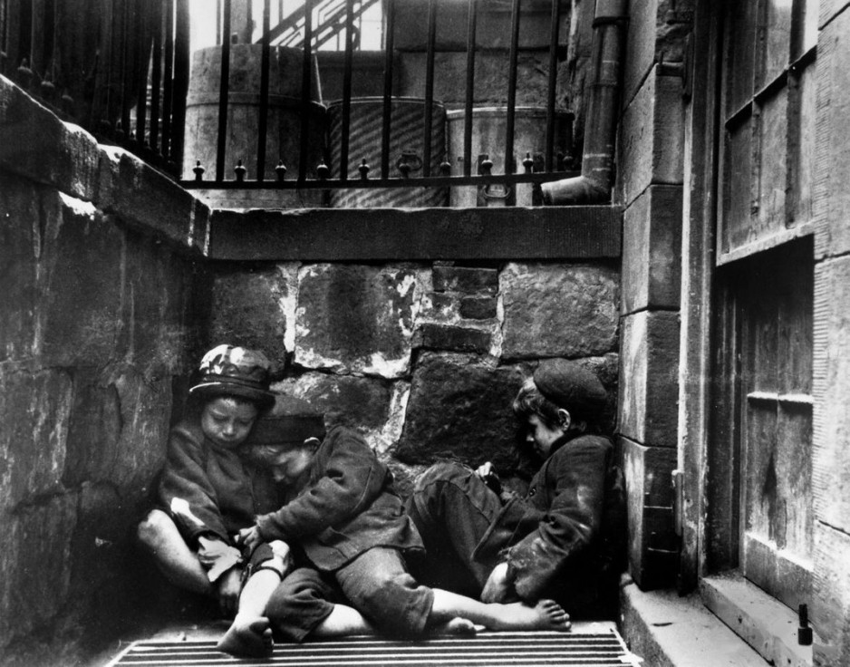Jacob Riis: Three Urchins Huddling for Warmth in Window Well on NY's Lower East Side, 1889