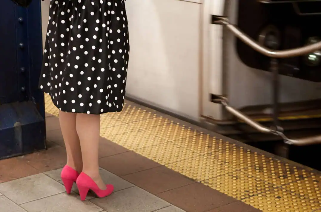 Woman with pink shoes and polka dot dress on the subway, New York color street photography print.