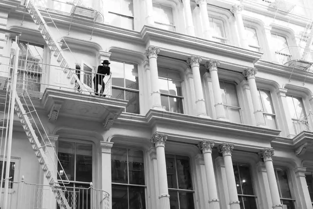 Man on fire escape balcony in SoHo cast-iron building, New York photography tour
